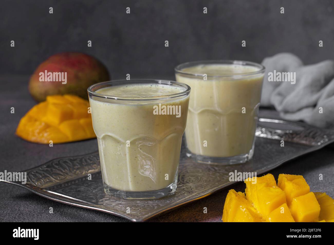 Lassi mangue en deux verres sur fond gris. Lassi indien frais fait de yaourt, épices, mangue et glace Banque D'Images