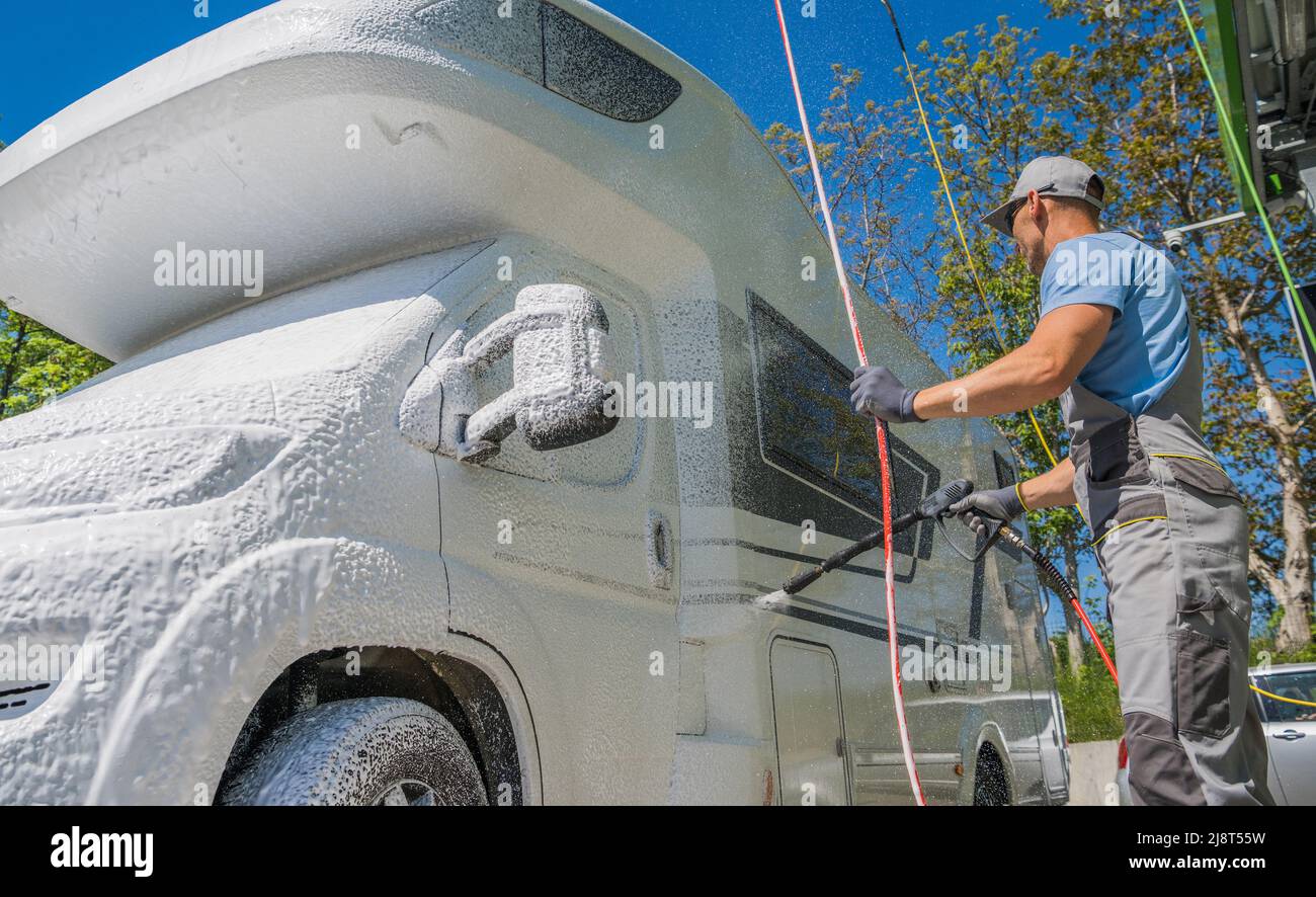 Caucasiens hommes dans sa 40s pression lavage moderne classe C camping-car Van RV avec mousse active. Entretien des véhicules récréatifs. Banque D'Images