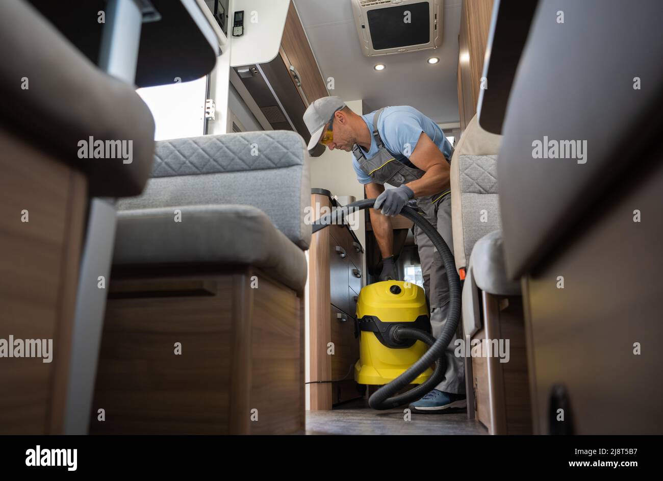 Nettoyage de l'intérieur de la fourgonnette camping-car. Travailleur caucasien dans son 40s avec aspirateur de qualité industrielle. Véhicules récréatifs thème. Banque D'Images