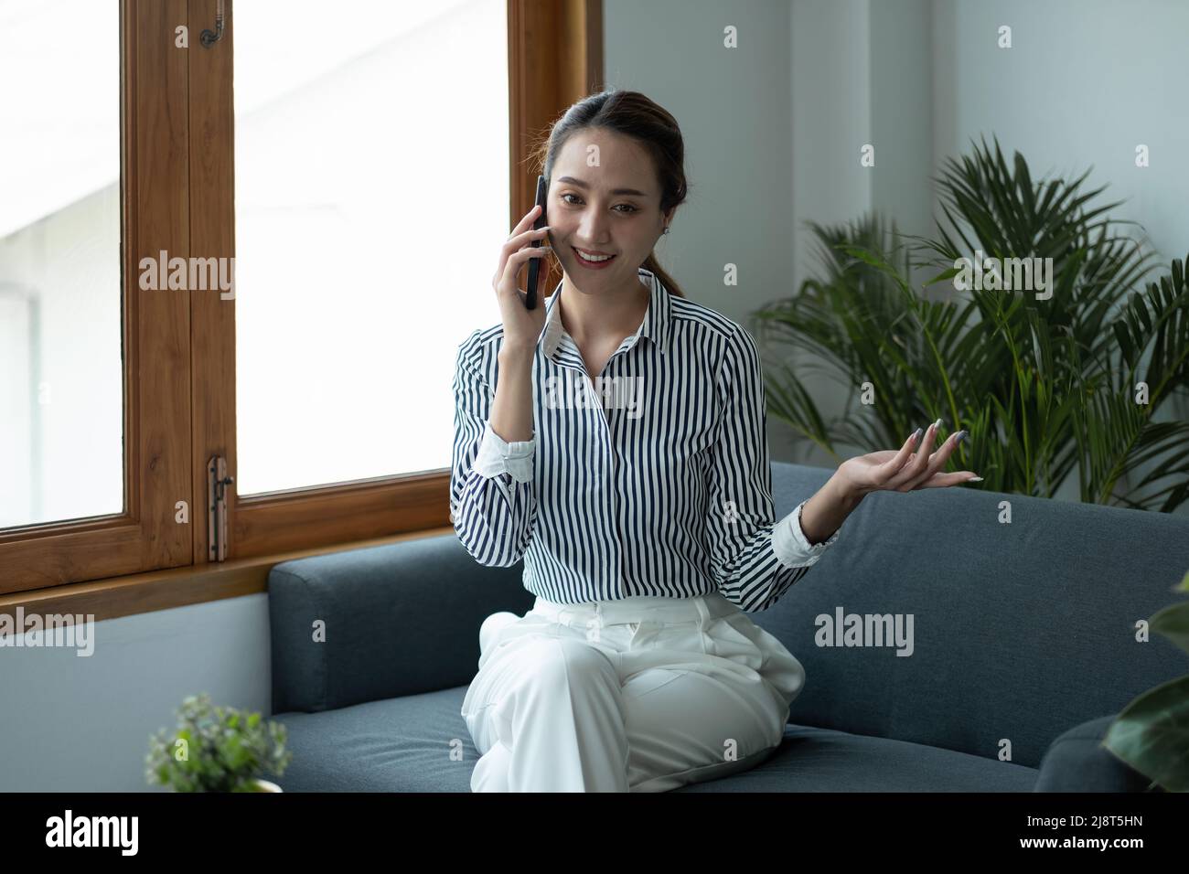 Femme d'affaires asiatique attrayante parlant sur téléphone mobile avec le client. Banque D'Images