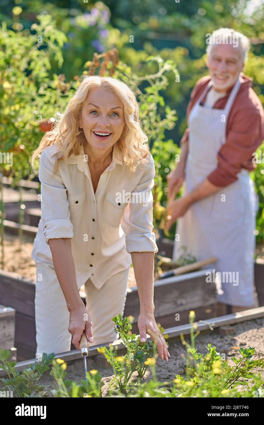 Femme souriant à la caméra travaillant près du potager Banque D'Images