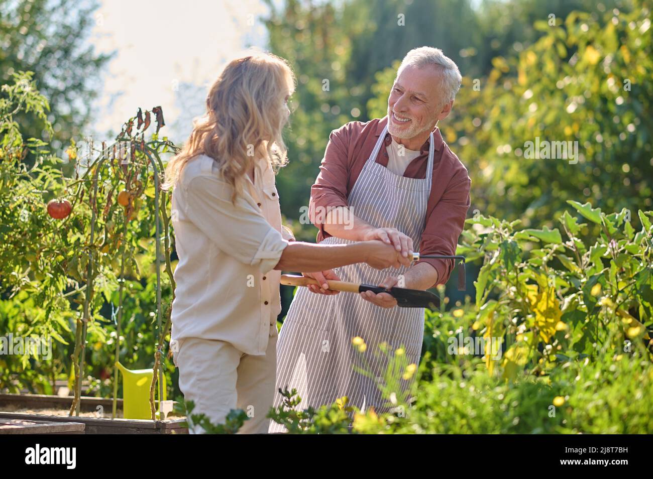 Femme et homme se donnant les autres outils de jardin Banque D'Images