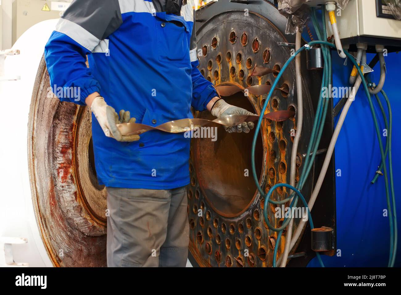 Un ingénieur en casque inspecte et répare les équipements à gaz de la chaufferie. Nettoyage et entretien de chaudière à vapeur industrielle. Banque D'Images