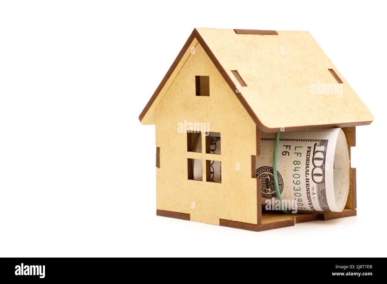 Rouleau de cent billets de dollars à l'intérieur d'une maison en bois modèle isolé sur blanc. Concept de dépôt hypothécaire. Banque D'Images