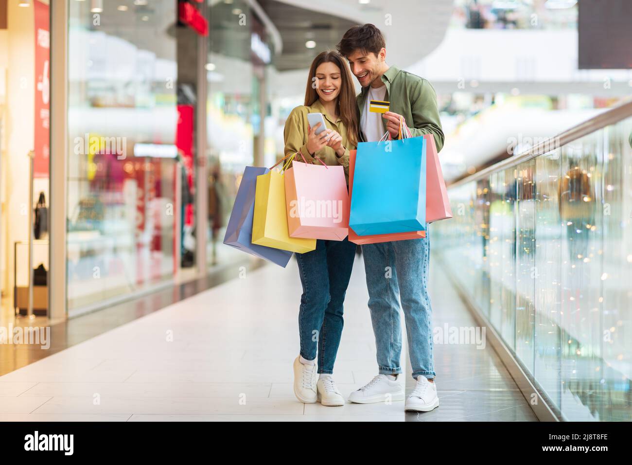 Couple Shopping en utilisant le téléphone et la carte de crédit dans Mall Banque D'Images