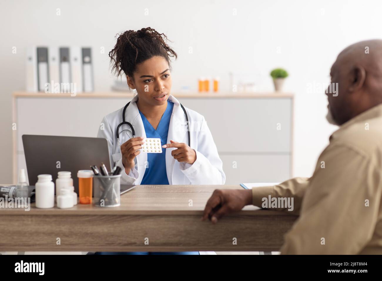 Femme médecin noir montrant des pilules à un patient mâle Banque D'Images Femme médecin noir montrant des pilules à un patient mâle Banque D'Images