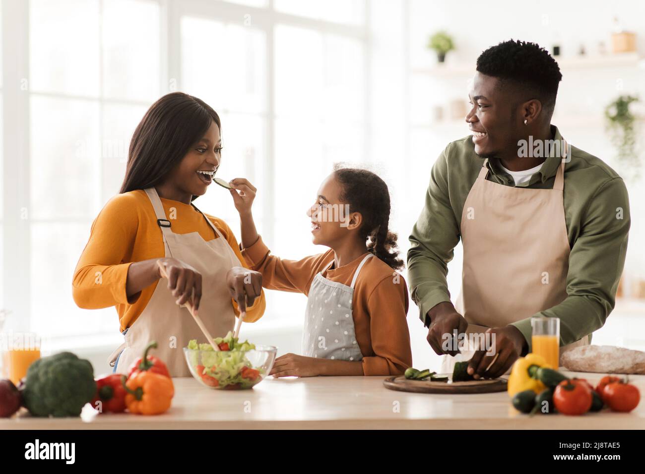 Une famille africaine se nourrissant les uns les autres en s'amusant en préparant une salade intérieure Banque D'Images