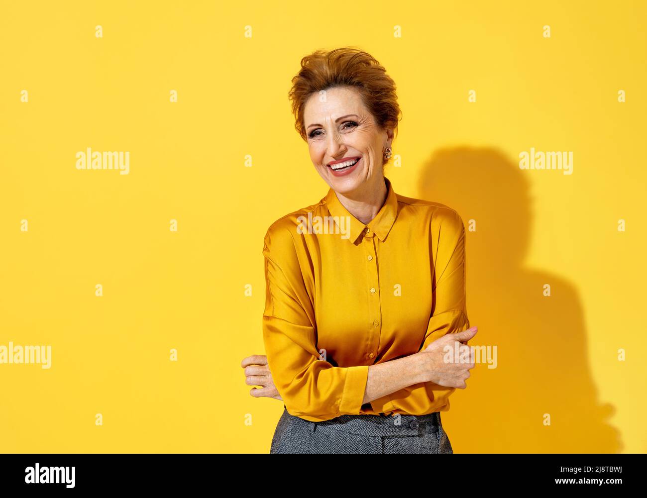 Bonne femme positive. Photo d'une femme âgée en chemise jaune sur fond jaune Banque D'Images