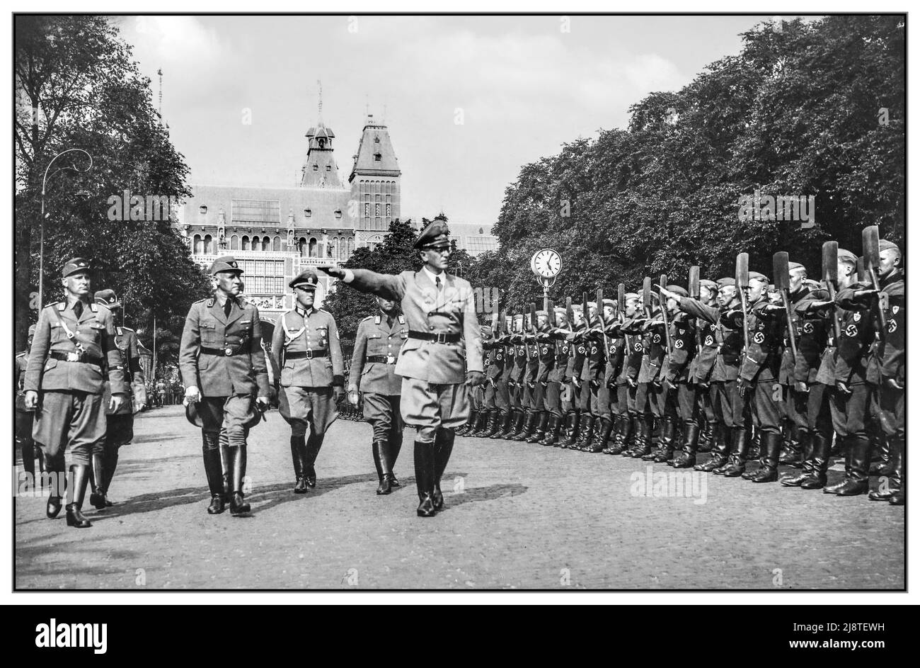 Nazis Dutch RAD Parade Reich Labor Work Service Parade uniforme avec des pelles à l'attention. Archive 1940s WW2 devant le Rijksmuseum; le Service allemand du travail du Reich est mis en place pour une parade du Reichsministre nazi Dr Seyss Inquart.; août 4; 1940 Amsterdam Hollande le Service du travail du Reich (Reichsarbeitsdienst; RAD) était une organisation importante établie en Allemagne nazie comme une agence pour aider les effets du chômage sur l'économie allemande, militariser la main-d'œuvre et endoctriner avec l'idéologie nazie. C'était le service officiel du travail de l'État, divisé en sections distinctes pour les hommes et les femmes Banque D'Images