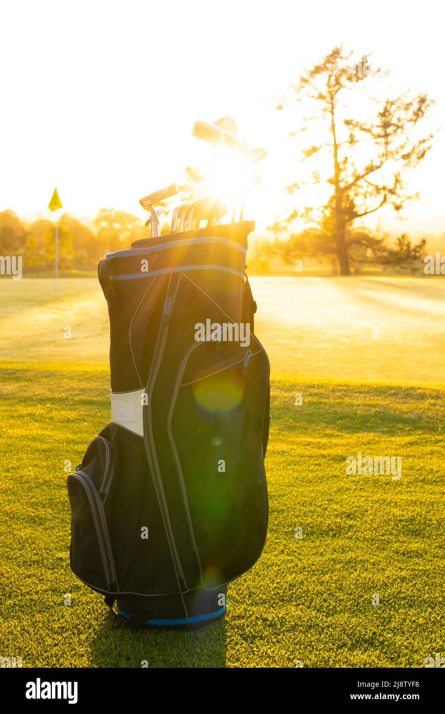 La lumière du soleil se diffuse à travers les clubs de golf dans un sac sur un paysage herbeux contre un ciel clair sur le parcours de golf Banque D'Images