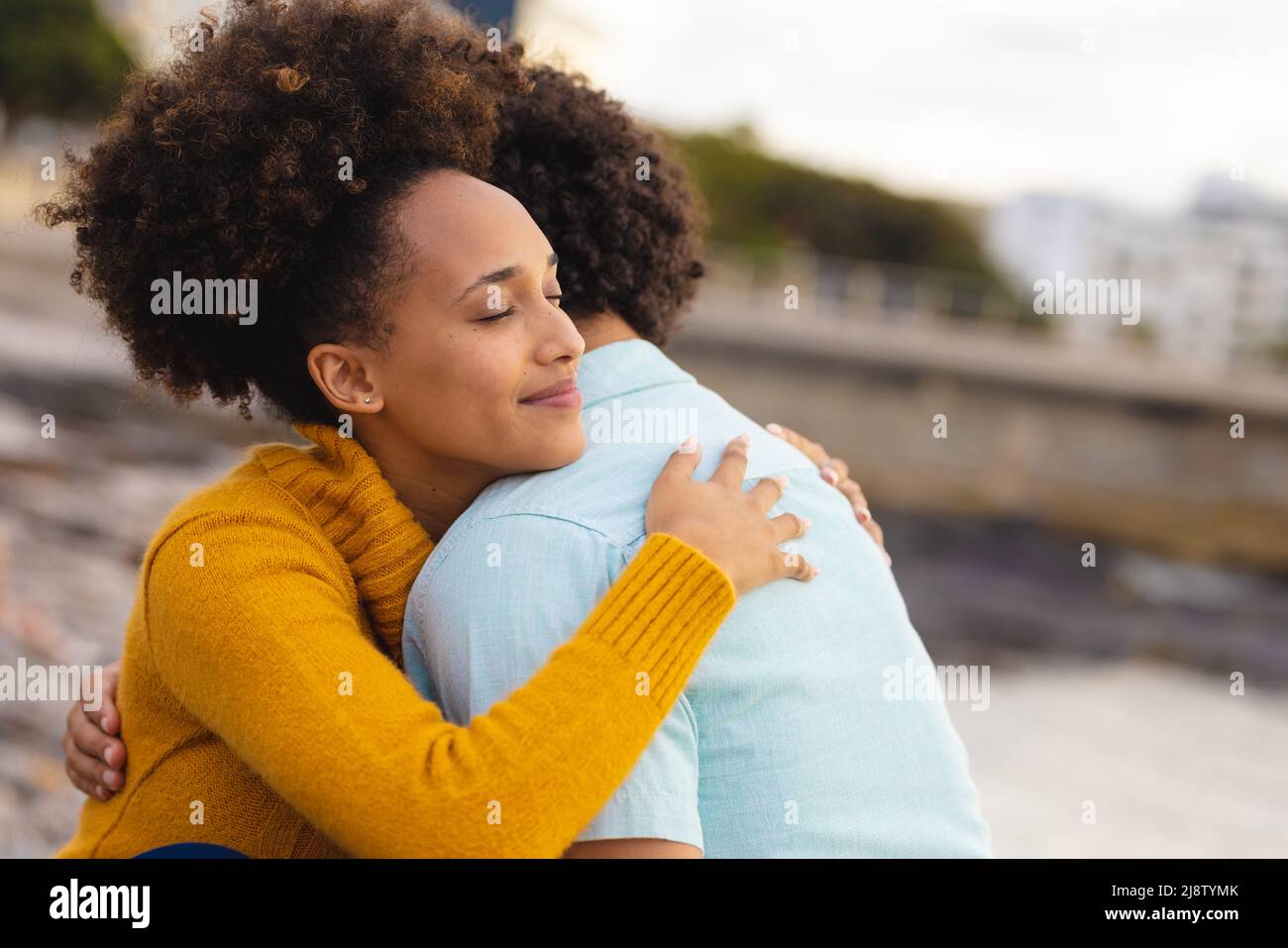 Jeune femme afro-américaine avec les yeux fermés embrassant un petit ami afro-américain à la plage Banque D'Images