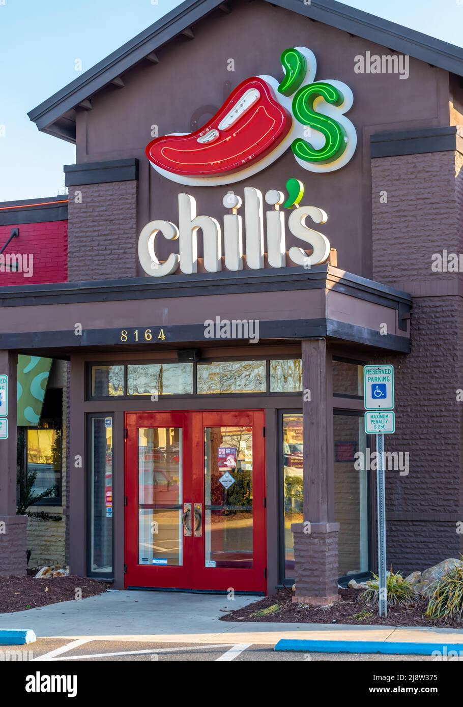 Photo extérieure moyenne de la façade du restaurant « Chili's » et de son logo au-dessus de l'entrée de la porte vitrée, dans la douce lumière du crépuscule. Banque D'Images