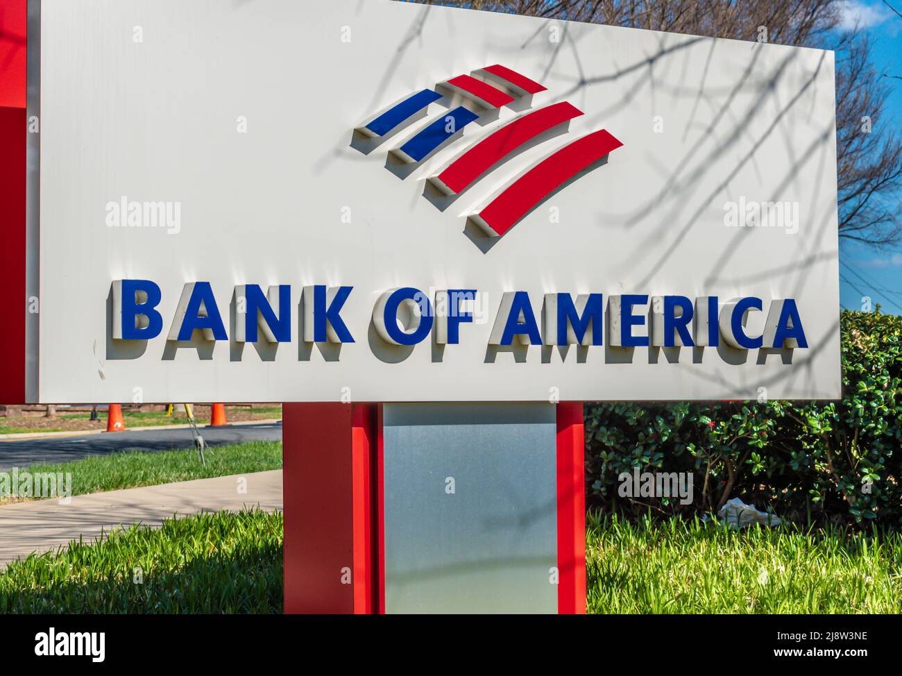 Extérieur, marque et logo « Bank of America » sur pied en rouge, blanc et bleu avec verdure et reflets par temps ensoleillé. Banque D'Images