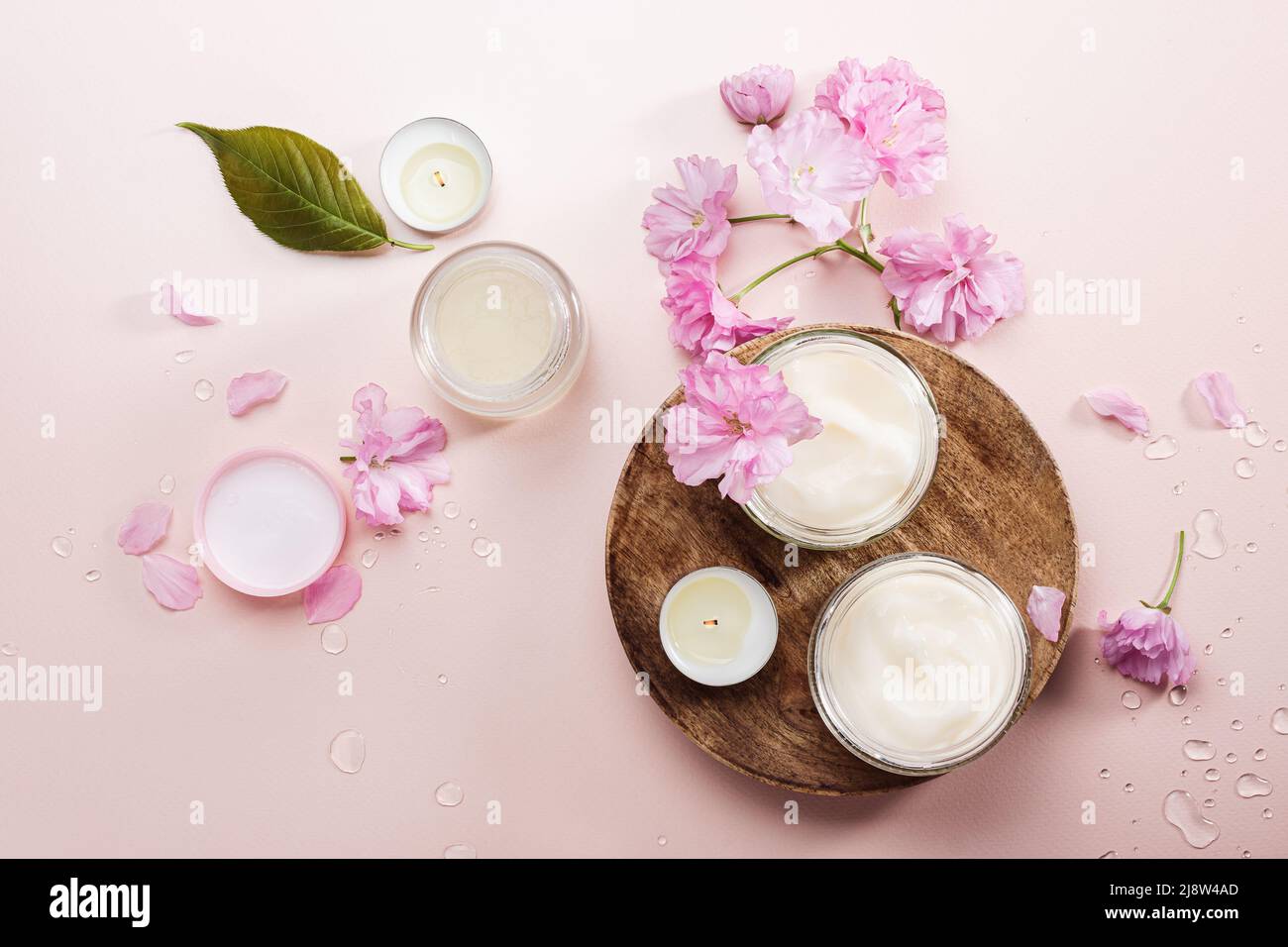 Crème de soin du corps naturelle et fleurs de cerise rose. Pose à plat. Banque D'Images