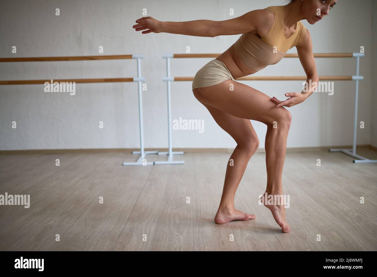 Jeune femme sportive vêtue de la couleur du corps qui répète la danse moderne dans un studio de danse Banque D'Images