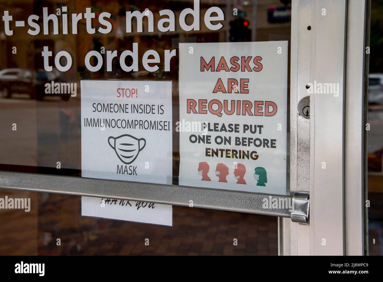 Lawrence, Kansas. Les masques faciaux sont obligatoires dans la fenêtre du magasin et quelqu'un est immunocompromis après que le gouvernement a levé l'exigence de masque. Banque D'Images