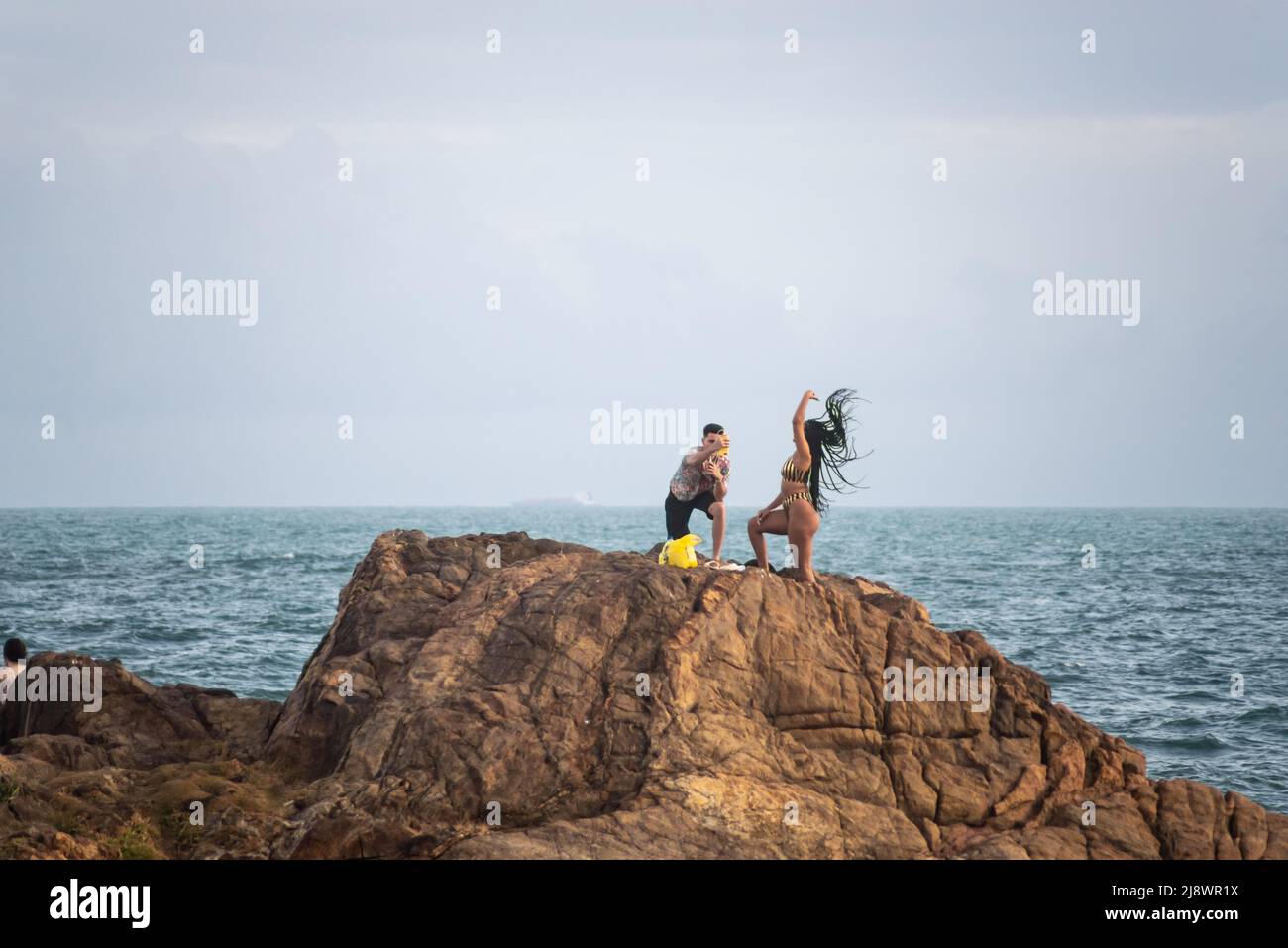 Homme et femme au sommet d'un grand rocher à la plage de Farol da Barra à Salvador, État de Bahia, Brésil. Banque D'Images