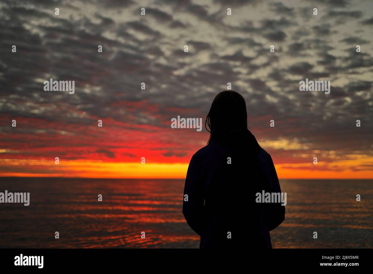 Une jeune fille de l'adolescence regarde dans l'admiration, l'émerveillement, et l'admiration à un magnifique ciel de coucher de soleil Banque D'Images