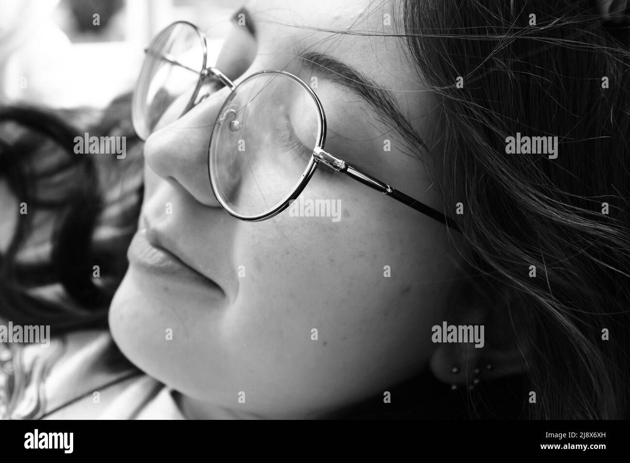 Photographie en noir et blanc d'une jeune fille avec des lunettes Banque D'Images