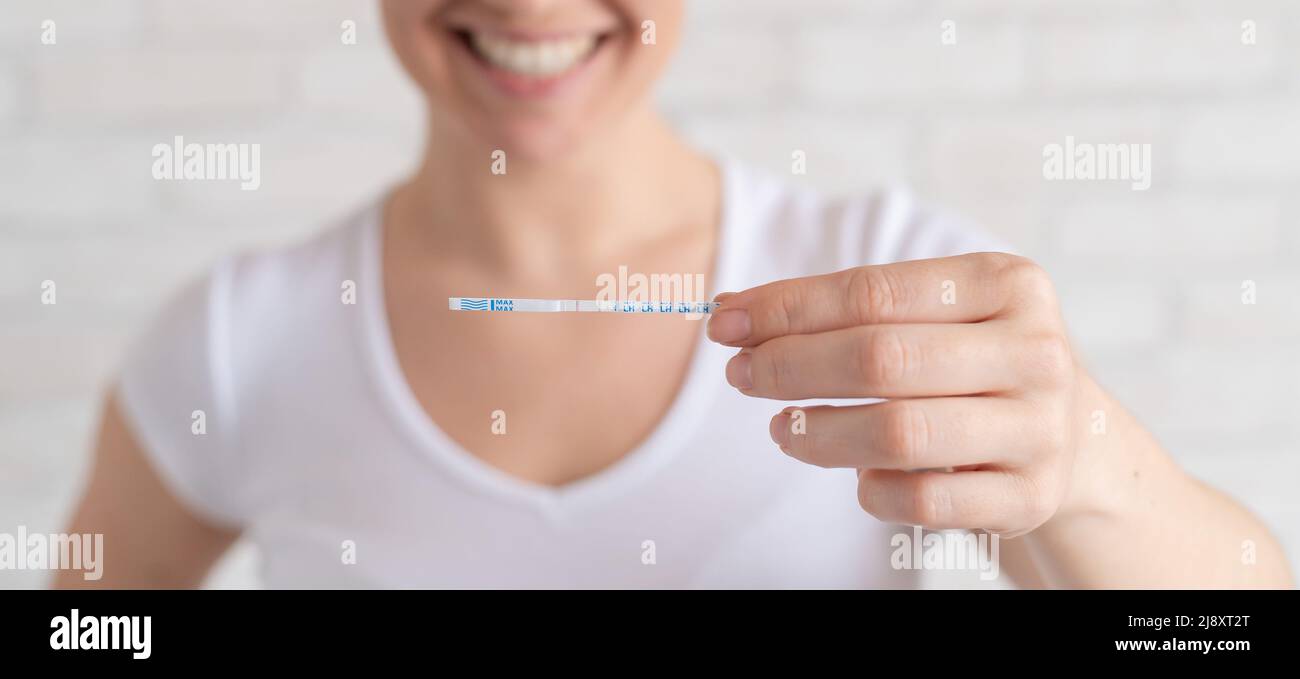 Une femme heureuse présente un test d'ovulation positif. Le concept de la fertilité féminine et de l'hormone lutéinisante élevée. Le bon moment pour concevoir un enfant. Banque D'Images