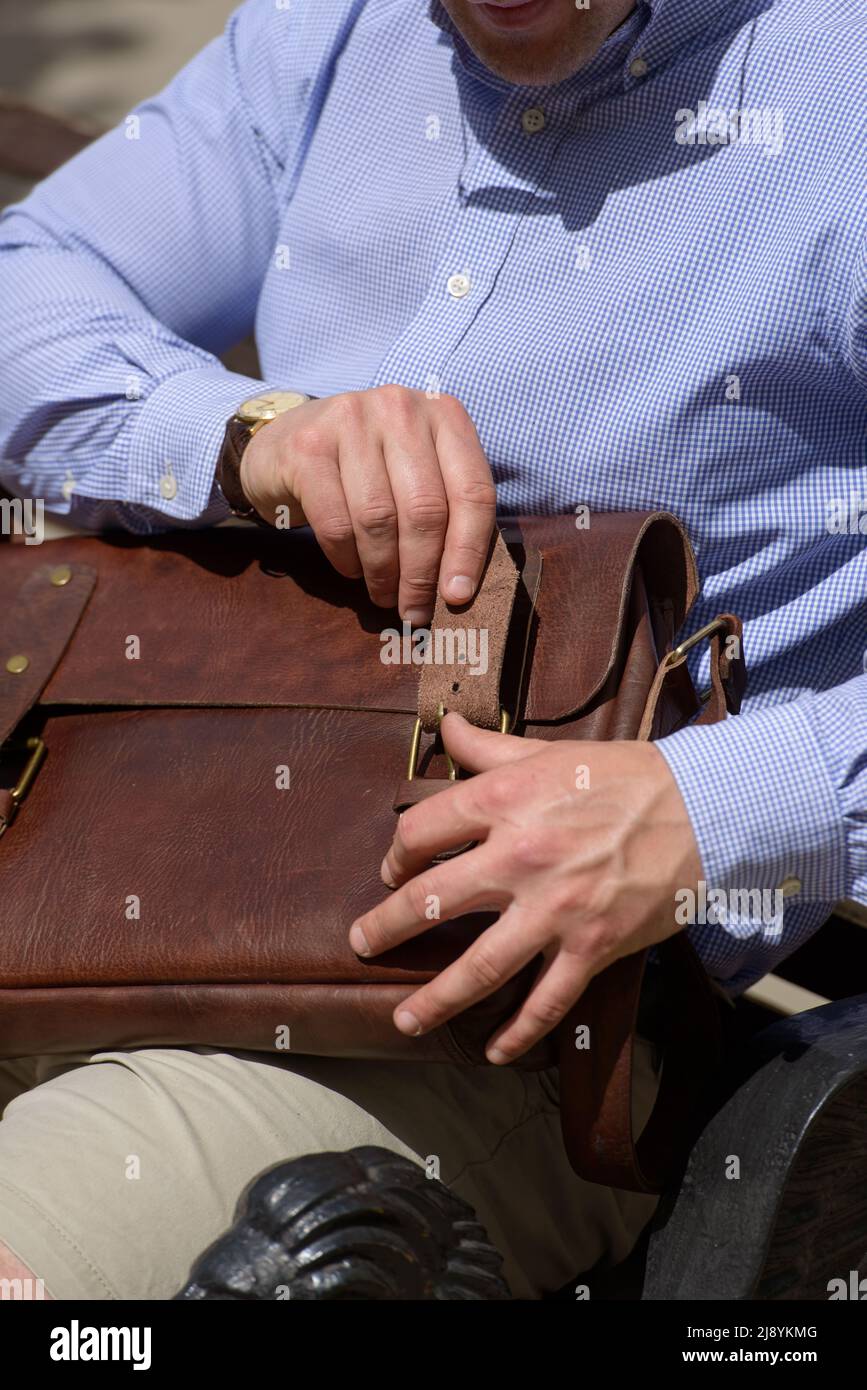 Photo partielle d'un homme avec un porte-documents en cuir marron avec un aspect ancien et rétro. Photo à l'extérieur Banque D'Images