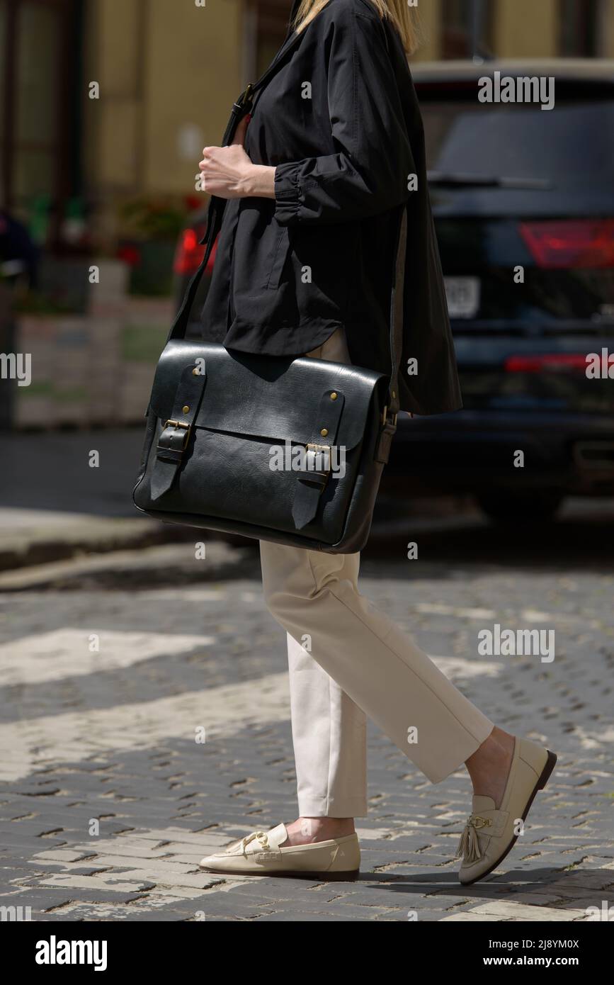 Photo partielle d'une femme avec un porte-documents en cuir noir à l'aspect ancien et rétro. Photo à l'extérieur Banque D'Images