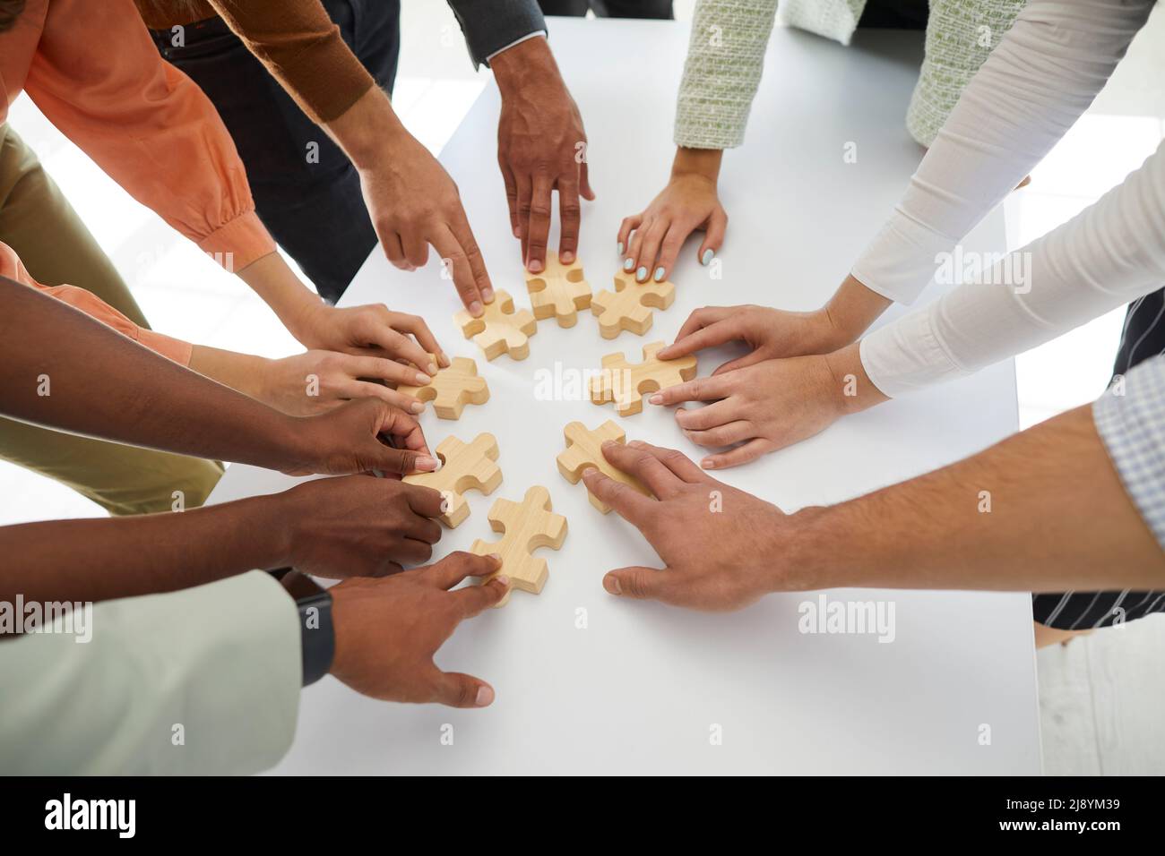 Une équipe multiraciale de gens d'affaires se joignant à des pièces de puzzle sur une table de bureau Banque D'Images