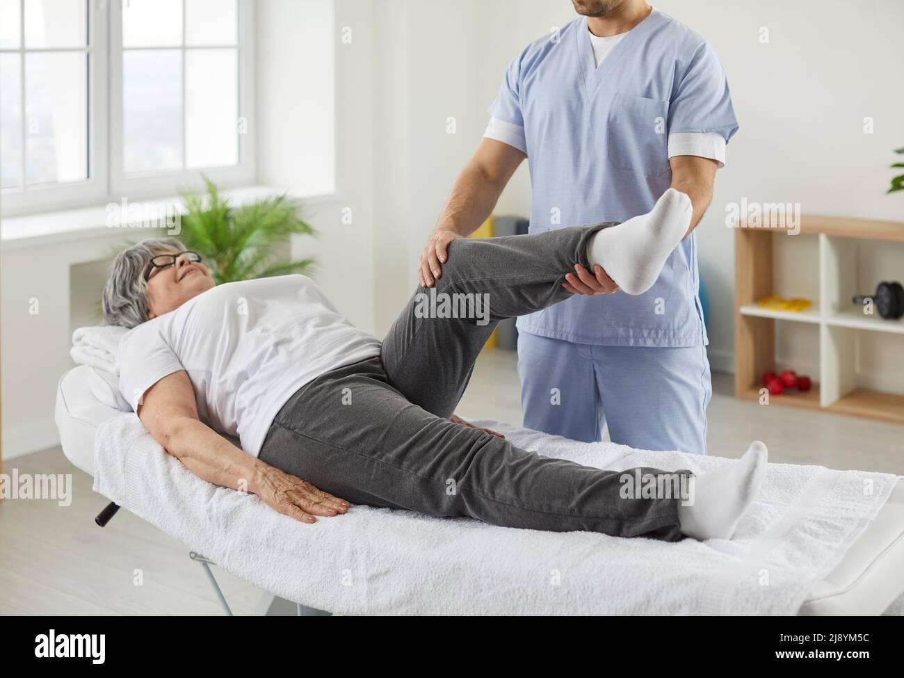 Chiropraticien, ostéopathe ou physiothérapeute examinant la jambe et le genou de la femme âgée Banque D'Images