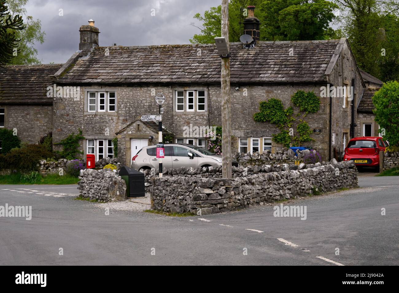 Calme Conistone village centre (belles propriétés en pierre de C18, jonction de route murée, signalisation) - Wharfedale, Yorkshire Dales, Angleterre, Royaume-Uni. Banque D'Images