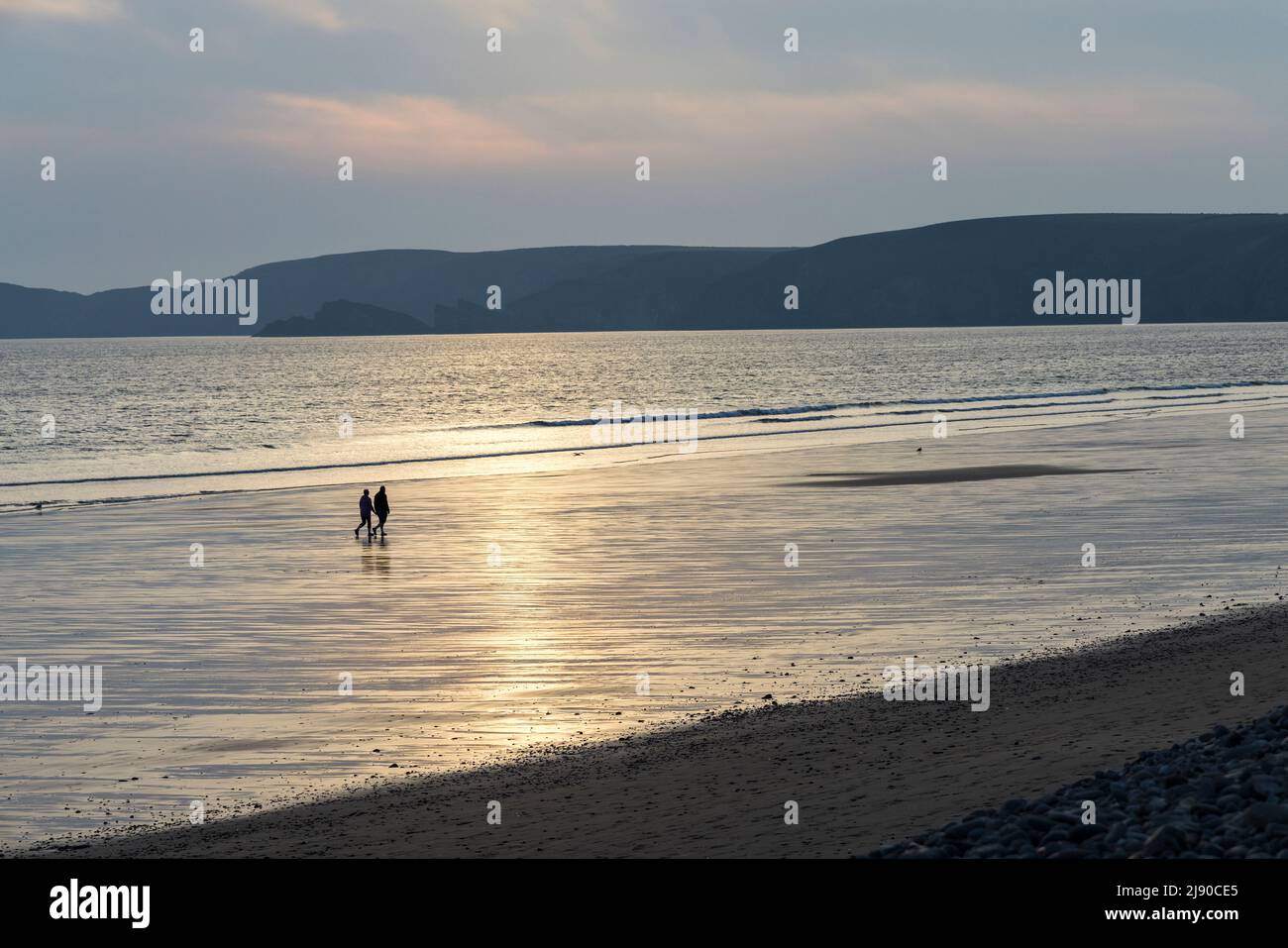 Deux personnes marchant sur la plage à Newgale au crépuscule, pays de Galles, Royaume-Uni Banque D'Images