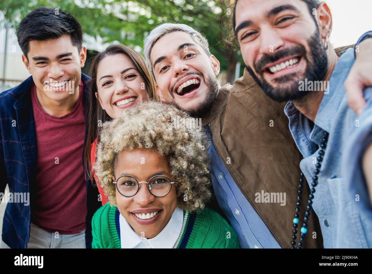 Groupe multiethnique d'amis s'amusant à prendre selfie en plein air - Focus sur le visage de l'homme central Banque D'Images