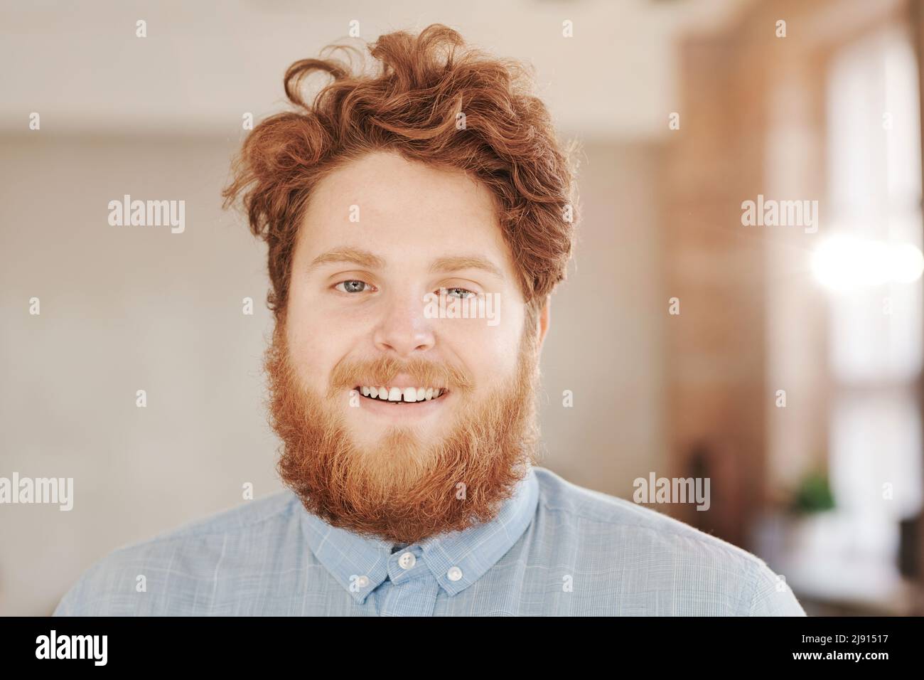 Portrait d'un homme souriant à tête rouge avec barbe et moustache debout dans un bureau moderne Banque D'Images