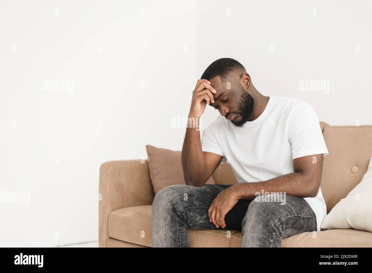 Se sentir stressé et contrarié. Frustré, un jeune homme beau se touchant la tête tout en se préoccupant de la rupture ou de la perte d'emploi et en gardant les yeux fermés pendant qu'il est assis Banque D'Images