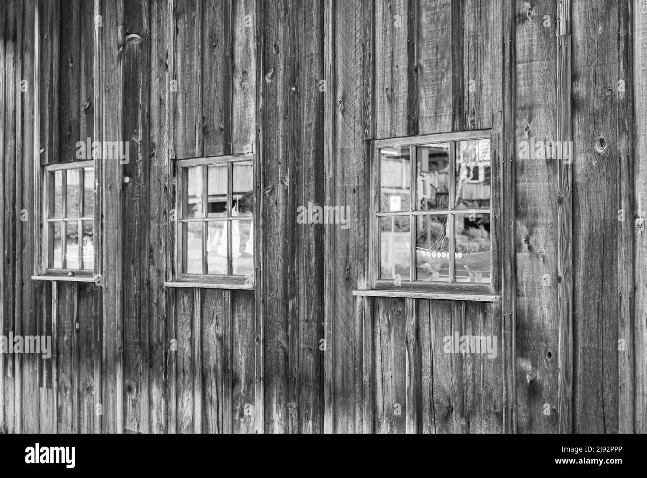 Fenêtres sur un mur de bois abîmé, arrière-plan abstrait grundy. Vieux mur délavé avec fenêtres d'une Grange. Photo de rue, personne, mise au point sélective Banque D'Images