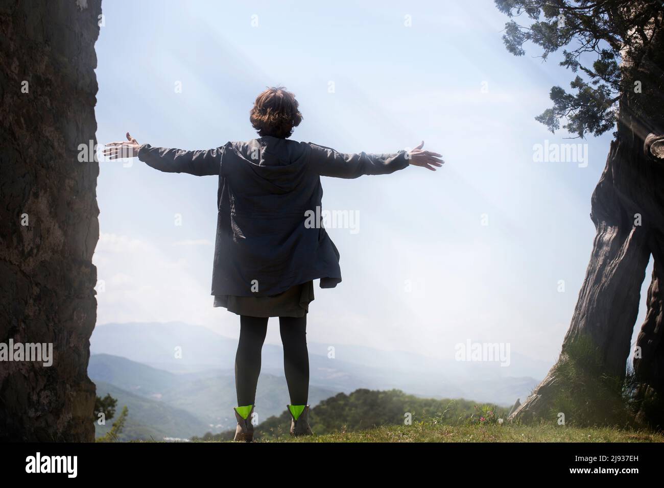Une jeune femme se tient au sommet d'une montagne avec ses bras étirés dans le vent au soleil. Le concept de liberté et de purification. Banque D'Images