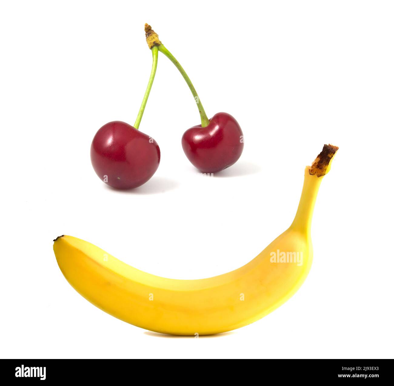 Banane et cerises isolées sur blanc. Sourire aux fruits, visage aux aliments Banque D'Images