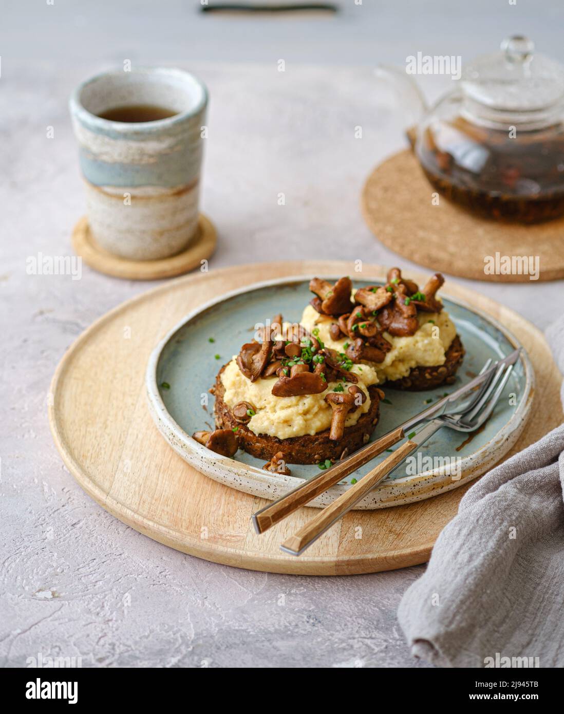 Petit déjeuner confortable avec œufs brouillés et chanterelle sur petits pains avec thé, espace copie Banque D'Images