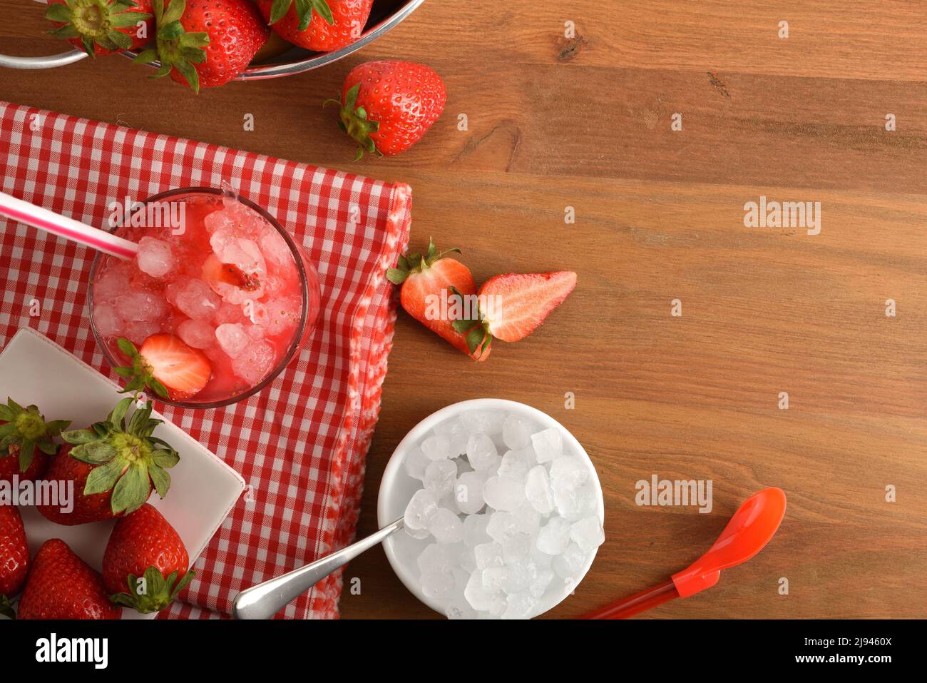 Granita de fruits avec fraises mûres et beaucoup de glace sur une table en bois avec un bol de glace et un panier rempli de fraises. Vue de dessus. Position horizontale Banque D'Images