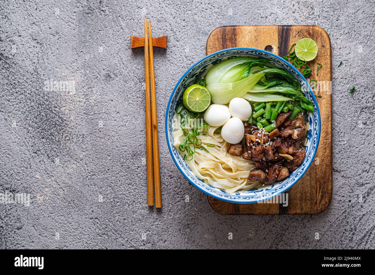 Soupe japonaise de ramen avec poulet, œuf, ciboulette et bok choy sur fond de béton. Banque D'Images