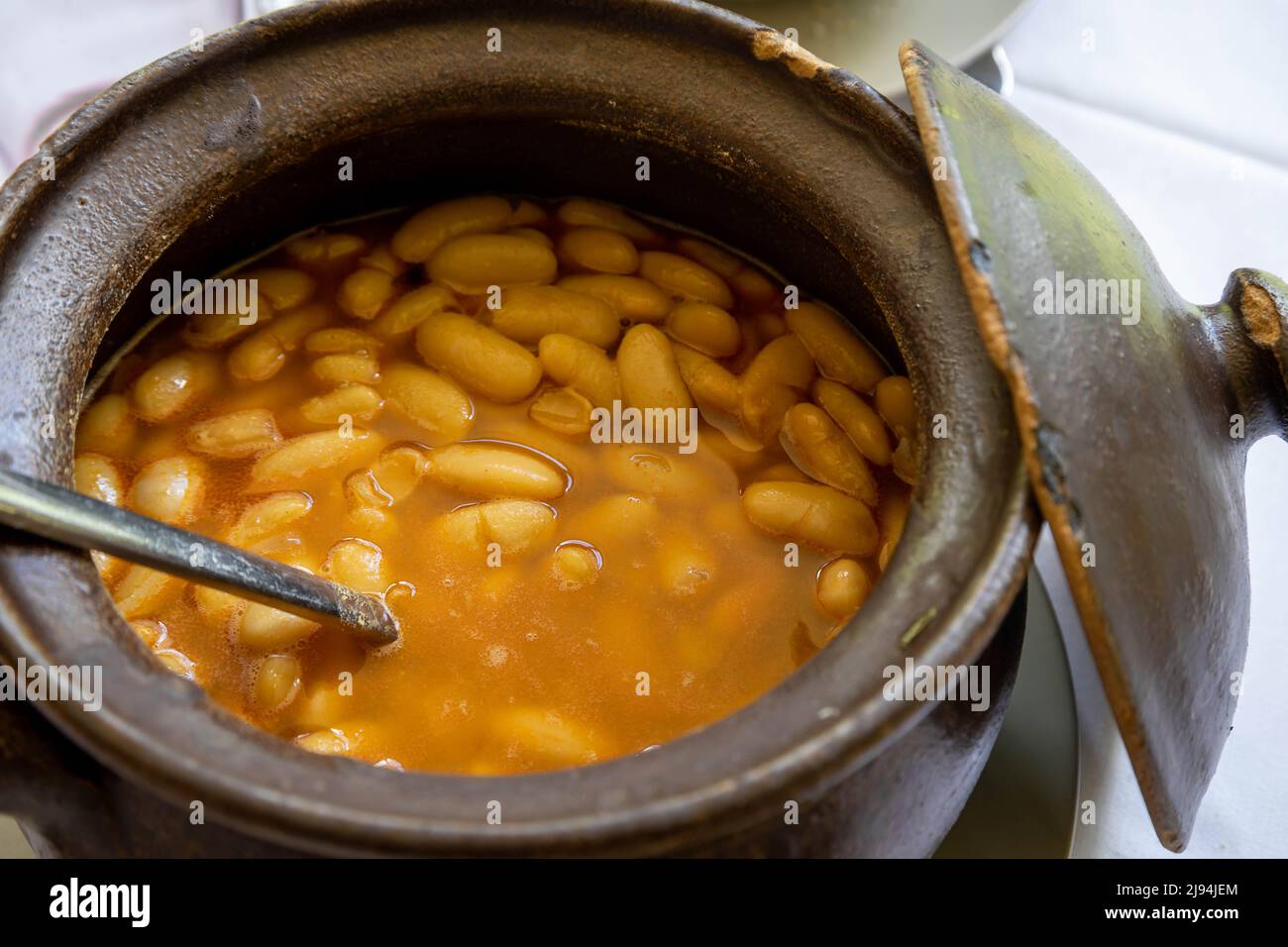 Gros haricots blancs provenant d'un ragoût de haricots Asturiens dans un pot en argile. Cuisine espagnole typique. Banque D'Images