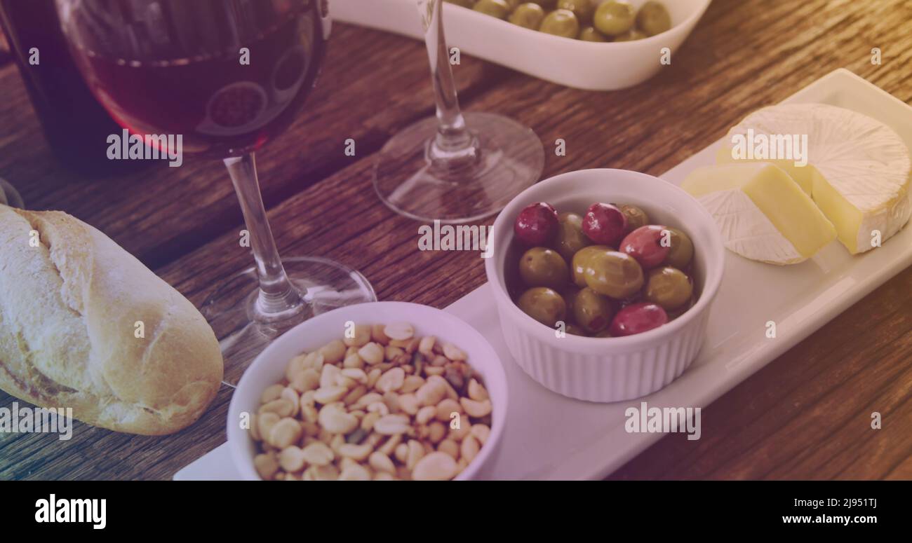 Image d'un verre de vin rempli de liquide jaune sur la table avec du vin et des encas Banque D'Images