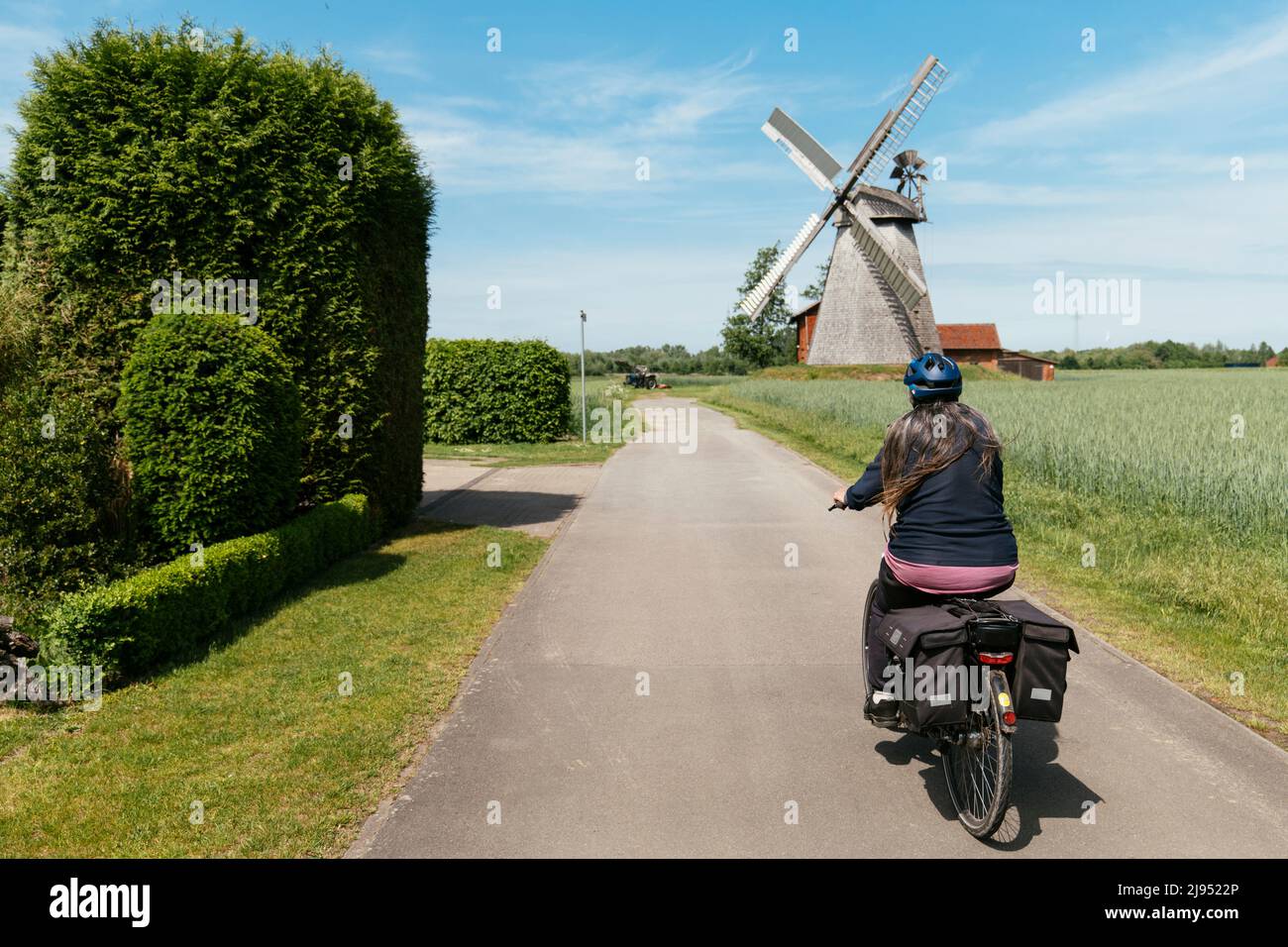 Femme sur un e-vélo à vélo vers le moulin à chaussettes à partir de 1802 à Petershagen-Bierde Banque D'Images