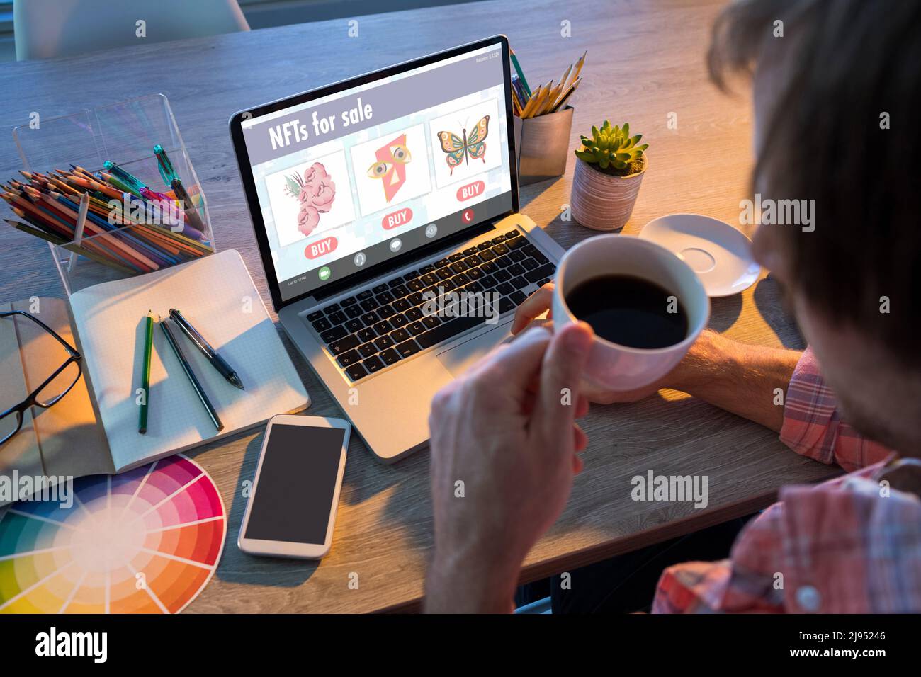 Homme d'affaires ayant du café noir tout en cherchant des jetons non fongibles sur ordinateur portable dans le bureau Banque D'Images