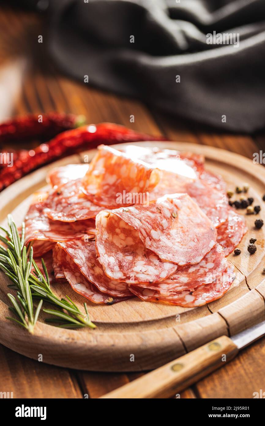 Tranché de saucisse italienne de salami avec du poivre sur une planche à découper. Banque D'Images