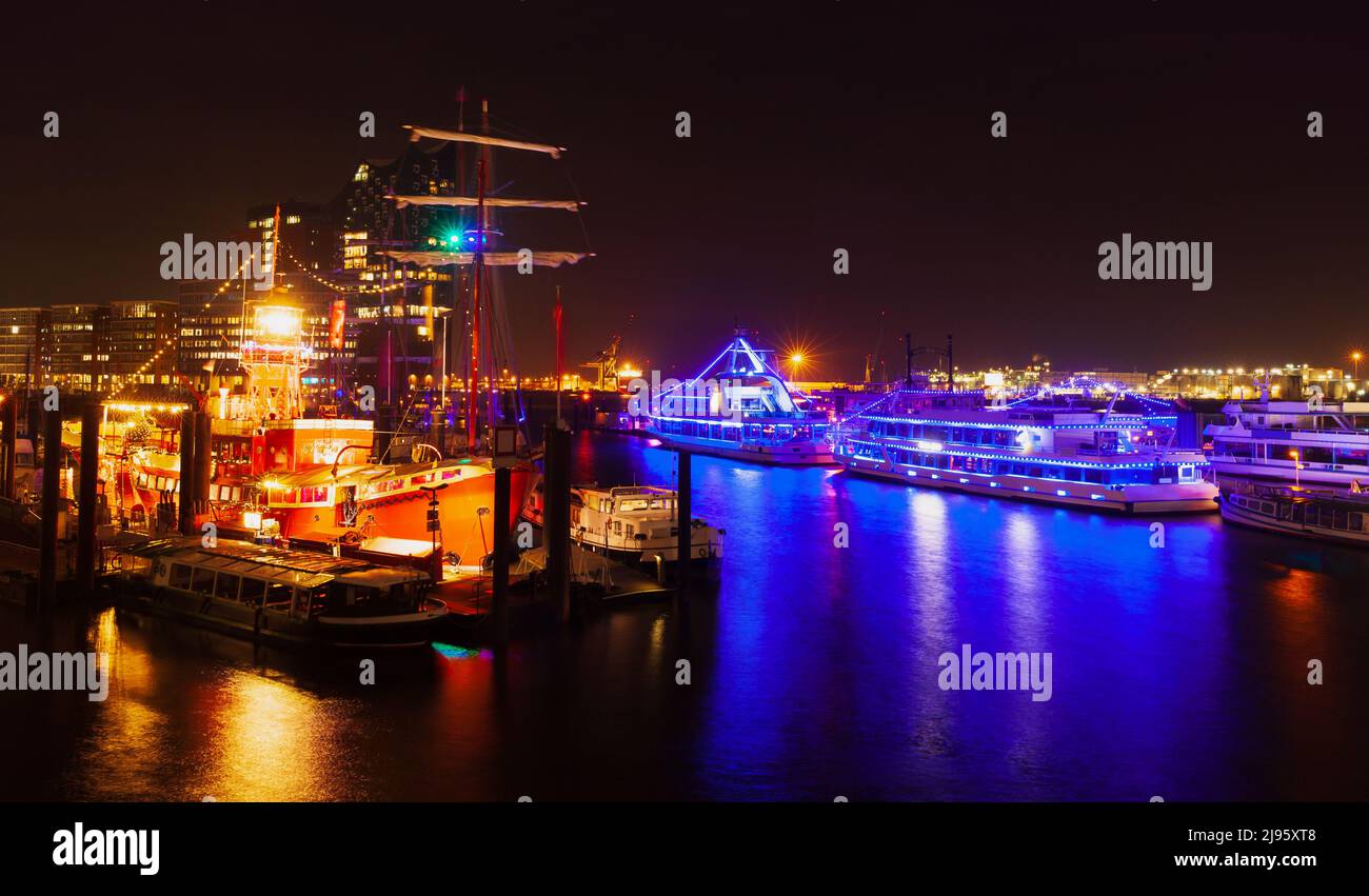 Vue nocturne sur la ville avec des navires éclairés et des restaurants flottants amarrés dans le vieux port de Hambourg, Allemagne Banque D'Images