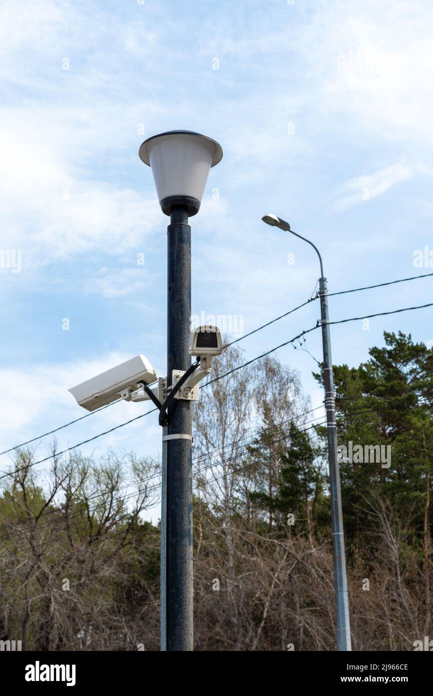 Caméras de surveillance montées sur un lampadaire sur le côté d'une route forestière. Caméra de vidéosurveillance de sécurité. Sécurité dans la ville. Le tournage caché de ce qui est happeni Banque D'Images