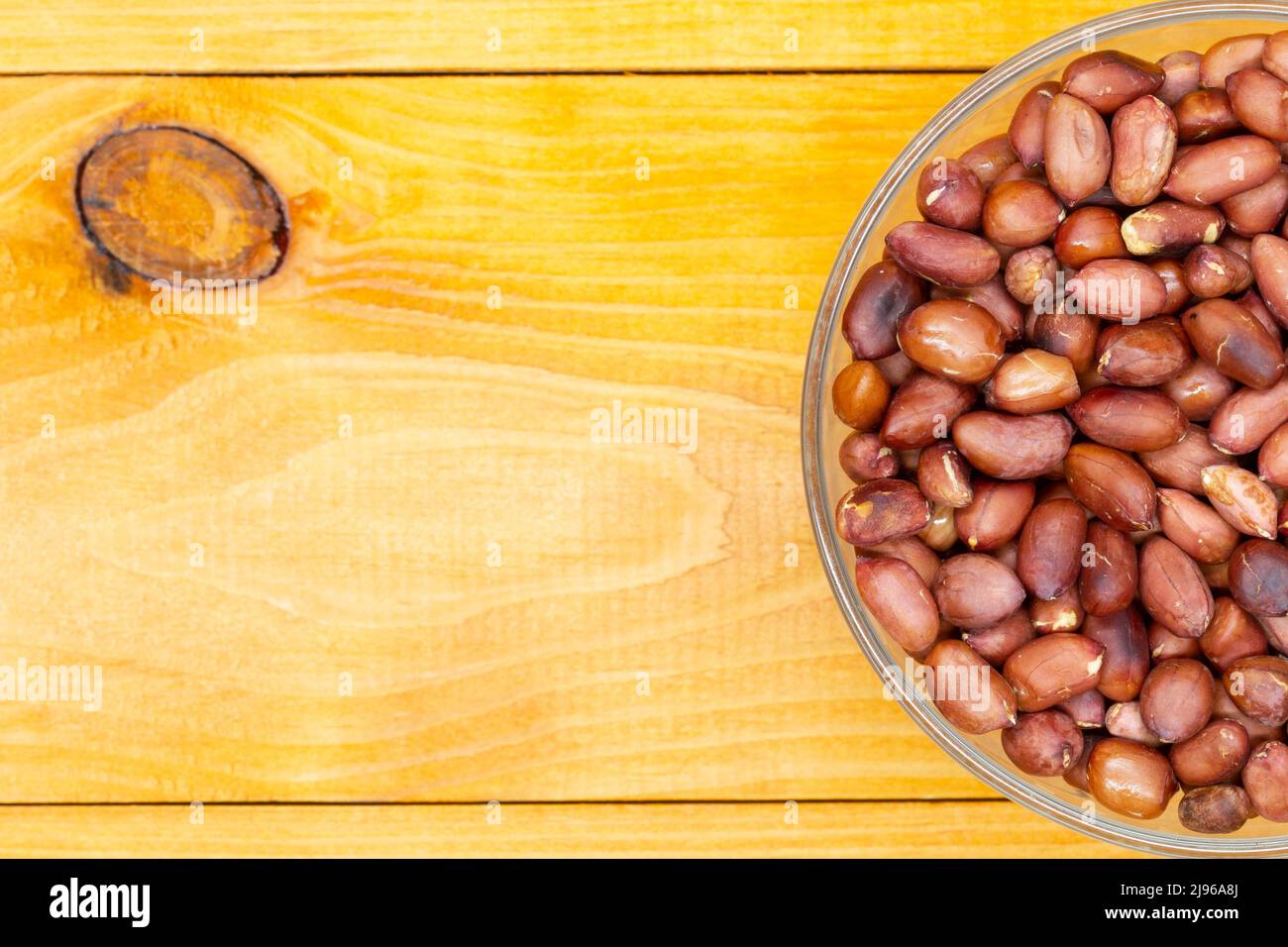 Cacahuètes grillées dans une tasse avec espace de copie pour le texte et la publicité. Arachides noix dans un pelage dans un bol transparent sur une table texturée en bois. La meilleure Banque D'Images