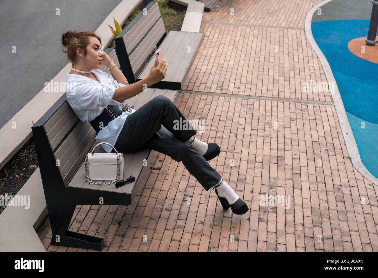 Homme vain androgyne prenant le selfie penché sur la porte noire dans la rue Banque D'Images