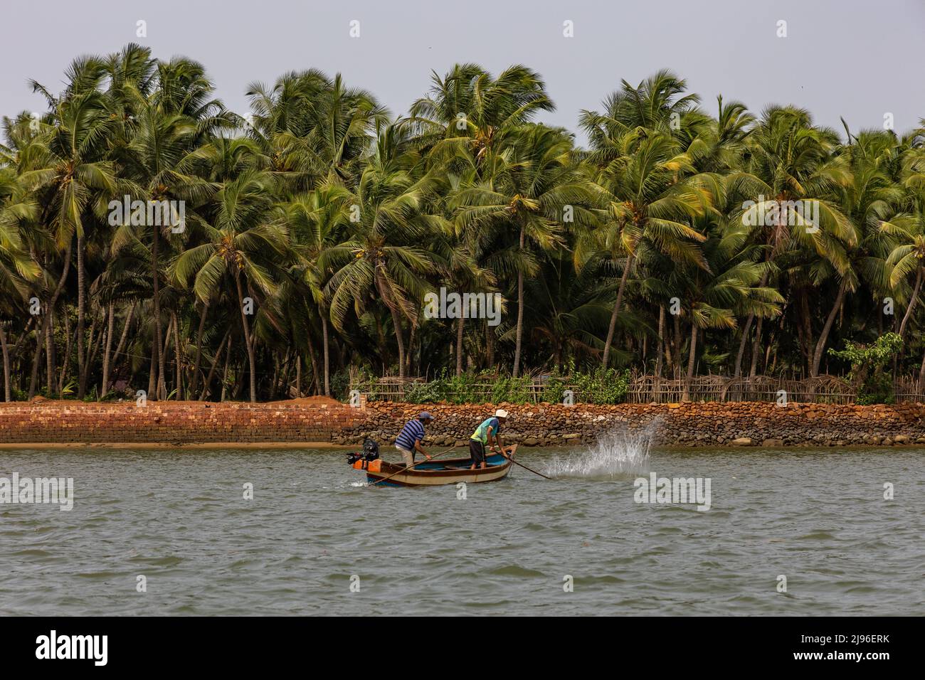 Un pêcheur qui bat l'eau avec un bâton pour amener de petits poissons dans le filet sur la rivière Karli. Banque D'Images
