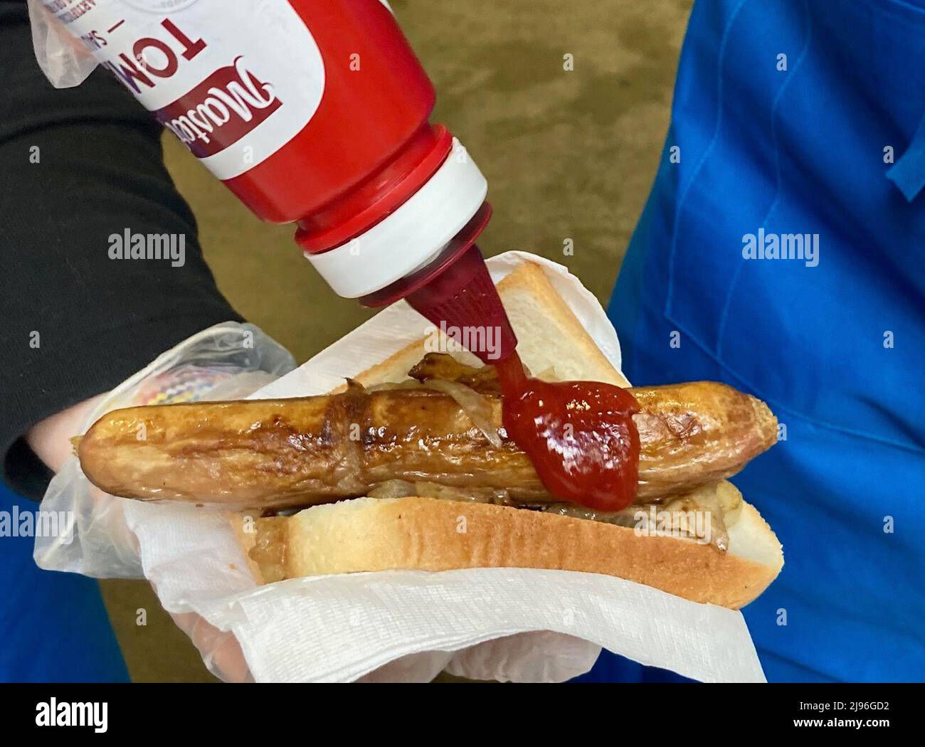 Sydney, Australie. 21st mai 2022. Les employés électoraux pressent le ketchup sur une saucisse à l'extérieur d'un bureau de vote à l'International Grammar School sur Kelly Street à Sydney, en Australie. Les saucisses de la démocratie sont une caractéristique spéciale des élections australiennes. Traditionnellement, il y a un grill devant de nombreux bureaux de vote où les électeurs peuvent manger une sorte de hot dog (K.wurst dans un pain doux avec de la moutarde et du ketchup). Pendant ce temps, il y a aussi des alternatives végétariennes et des stands avec café et gâteau. Crédit : Carola Frentzen/dpa/Alay Live News Banque D'Images